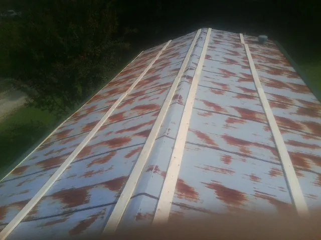 Rusted metal roof panels with new wood purlins before replacement in Indian Hills