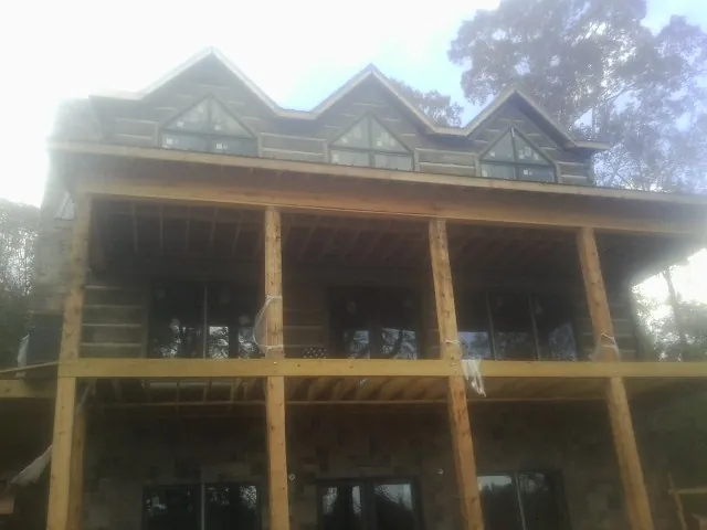 Dormers and porch framing on a large log home under construction — Roof Coating work by our crew in Indian Hills