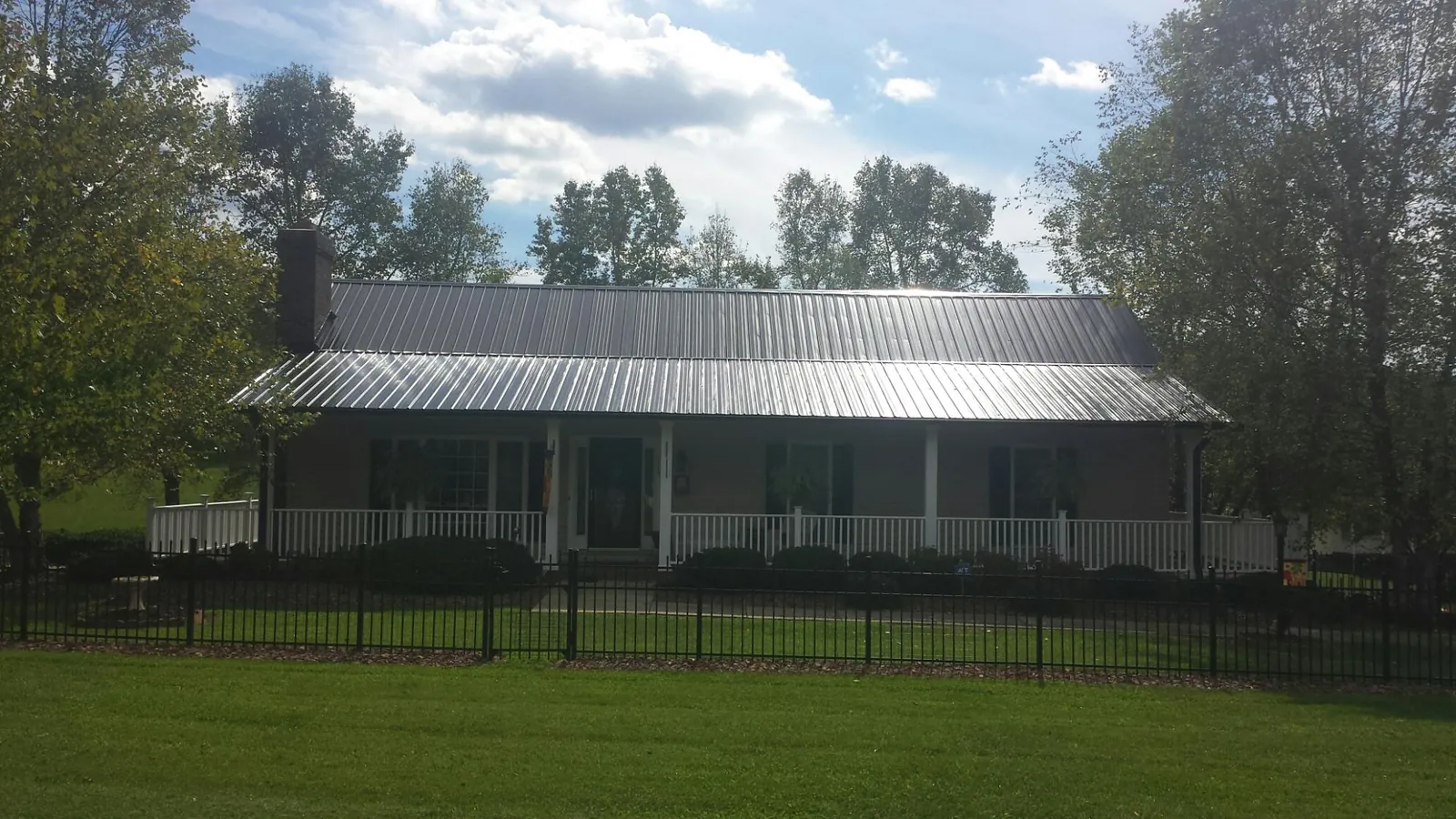 Gray metal roof on a brick ranch with a full width front porch — Gutter Guard Installation work by our crew in Indian Hills