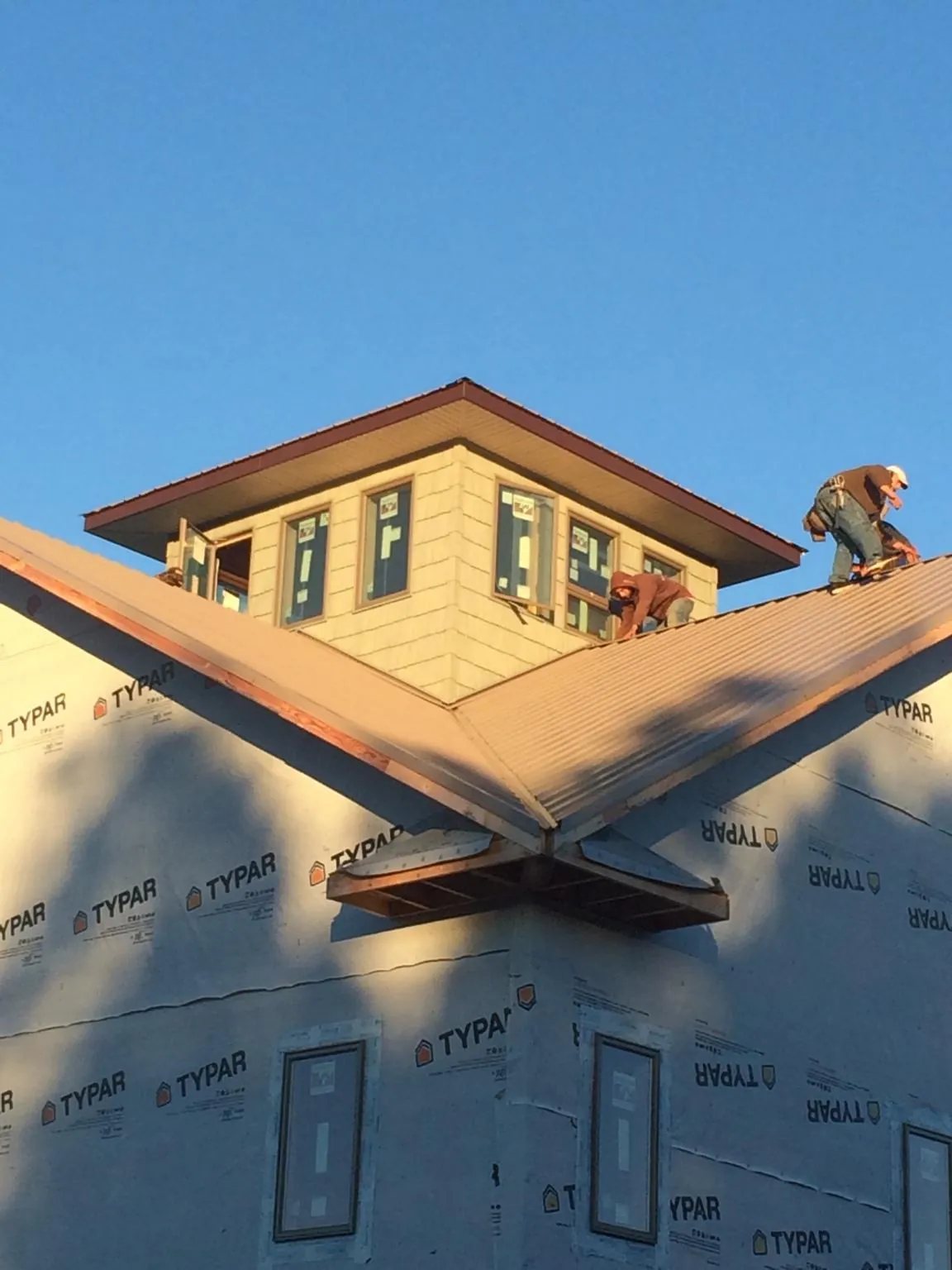 Roofers working around a rooftop cupola on a new metal roof at sunset — Roof Waterproofing in Indian Hills by Roofing Brothers